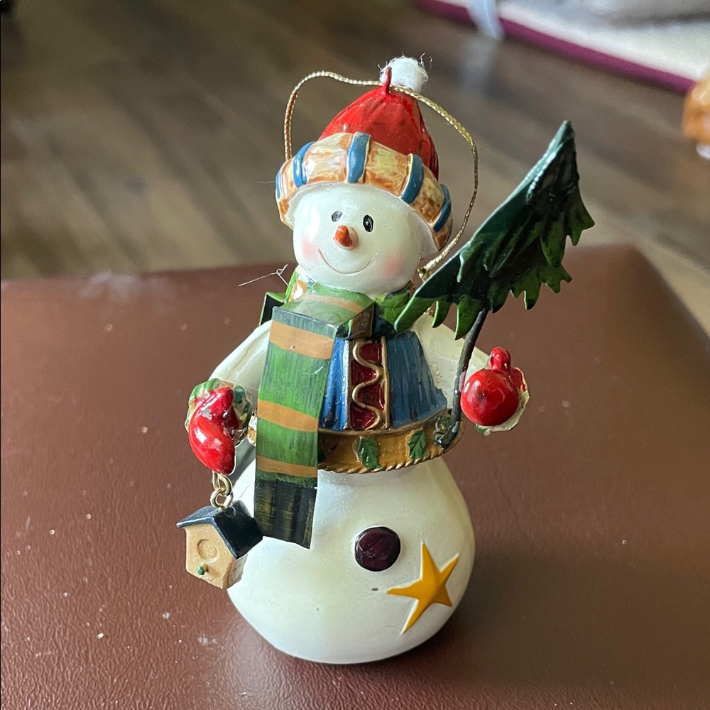 Festive Snowman Holiday ornament holding a tree and a bird house